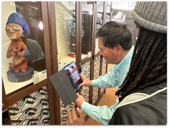 Visitor engaging with an augmented reality station in the Augmented Curiosities exhibition.